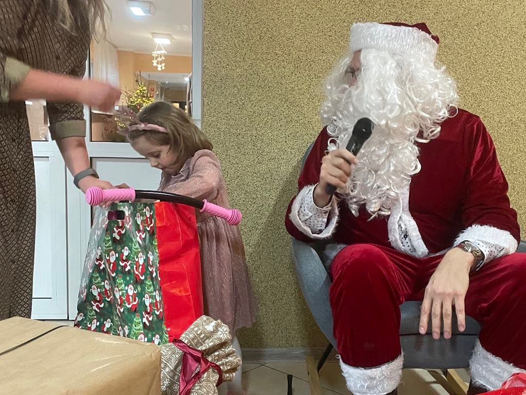 Mikołaj wręczający świąteczny prezent dziecku podczas akcji